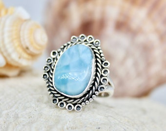 May include: A silver ring featuring a blue and white gemstone set in an ornate silver setting.