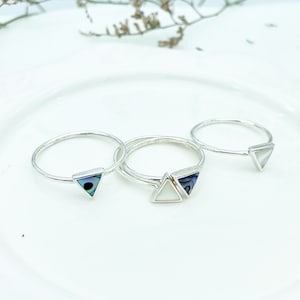 May include: Three silver rings with triangular shaped stones. The stones are white, iridescent, and blue.