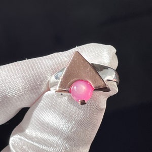 May include: A silver ring with a pink gemstone set in a triangular design.