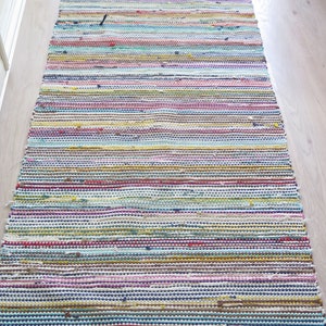 May include: A colorful striped rug with a woven texture. The rug is made of various colors, including blue, green, yellow, pink, and red.
