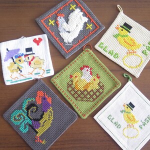 Puede incluir: Seis posavasos de cocina bordados con un tema de pollitos de primavera. Los posavasos son cuadrados y presentan diferentes diseños, incluyendo un gallo, una gallina con pollitos, un pollito con un sombrero de copa y un pollito con un paraguas. Los posavasos están hechos de tela blanca, gris y verde.