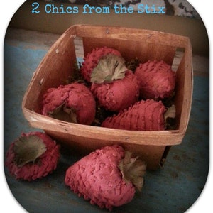 May include: A wooden crate filled with red felt strawberries. The crate is sitting on a blue and green surface. The text "2 Chics from the Stix" is visible on the top of the image.
