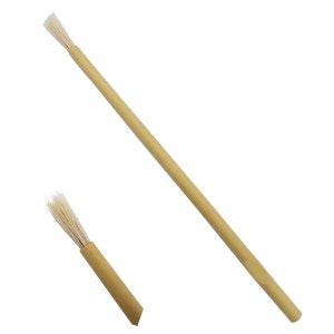 Op de afbeelding: Een lange, slanke kwast met een lichtbruine houten steel en witte haren, vergezeld van een apart, korter segment van dezelfde steel met bijpassende witte haren aan de bovenkant, geïsoleerd tegen een effen witte achtergrond.