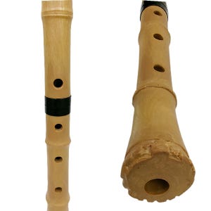 May include: A light brown bamboo flute featuring a cylindrical body with multiple circular finger holes and a black band around the centre. The instrument has a flared, textured base with a central opening, showcasing natural wood grain patterns.