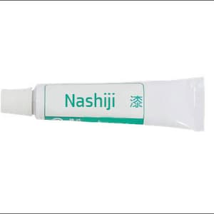 Puede incluir: Un tubo blanco de crema para la piel de la marca Nashiji con texto verde y un carácter japonés. El tubo tiene una tapa blanca.