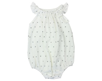 May include: White baby onesie with a black and white cross pattern and ruffled sleeves.