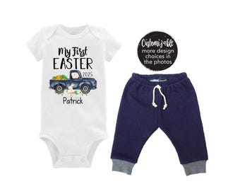 Puede incluir: Un body blanco con el texto "My First Easter 2025" y un camión azul con un conejito y zanahorias. El texto "Patrick" está debajo del camión. Un pantalón azul marino con un cordón blanco.