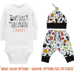 以下が含まれることがあります： 白地に黒とオレンジ色の文字で「My First Halloween Owen」と書かれた長袖ロンパース。白と黒のハロウィン柄の帽子とズボン。