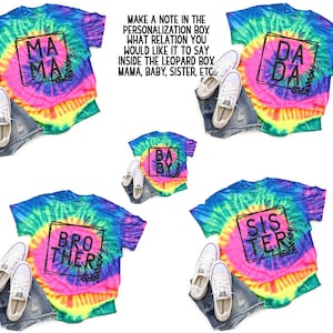 May include: Five tie-dye t-shirts with different text inside a black square. The text on the shirts reads "Mama", "Da Da", "Baby", "Brother", and "Sister".