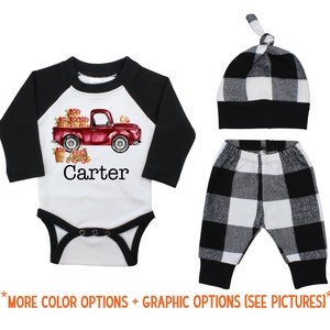 May include: A baby outfit set with a white bodysuit featuring a red truck with apples and the name "Carter", black and white checked trousers, and a black and white checked hat.