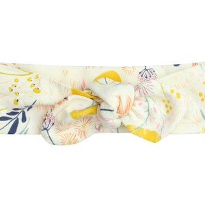 May include: A white headband with a floral pattern in shades of yellow, pink, and blue. The headband is tied in a knot at the top.