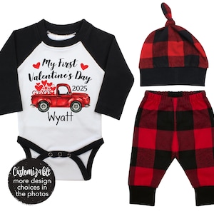May include: A red and black baby outfit with a red truck carrying hearts and the text "My First Valentine's Day 2025 Wyatt". The outfit includes a long-sleeved shirt, pants, and a hat.