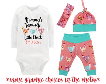 May include: A white long-sleeve bodysuit with the text "Mommy's Favorite Little Chick Brixton" and a graphic of three colorful chickens. The set also includes a pink headband with a chicken print, a pink and turquoise hat with a chicken print, and pink and turquoise leggings with a chicken print.