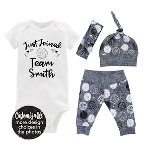 Könnte beinhalten: Ein weißer Baby-Strampler mit schwarzem Text, der "Just Joined Team Smith" lautet, und einer Volleyball-Grafik. Ein graues und weißes Stirnband, eine graue und weiße Mütze mit Volleyball-Muster und graue und weiße Leggings mit Volleyball-Muster sind ebenfalls enthalten.