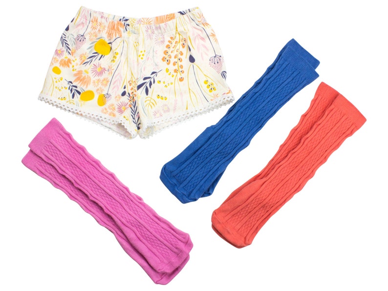 May include: Three pairs of knit leg warmers in pink, blue, and coral. The leg warmers have a cable knit pattern.