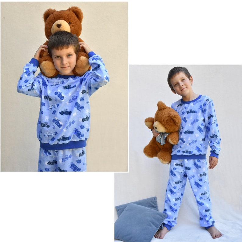 May include: A blue and white pajama set with a motorcycle print. The pajamas feature a long-sleeved top and matching pants. A brown teddy bear is included in the image.