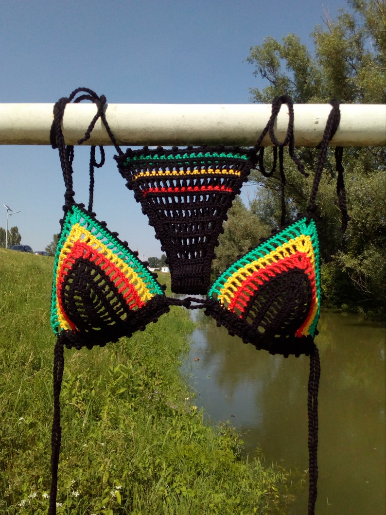 May include: A black crochet bikini top with green, yellow, and red stripes. The top is tied at the neck and back.