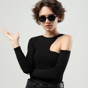 Woman wearing black round sunglasses in a wider fashion portrait, showing the overall scale and styling of the frame.
