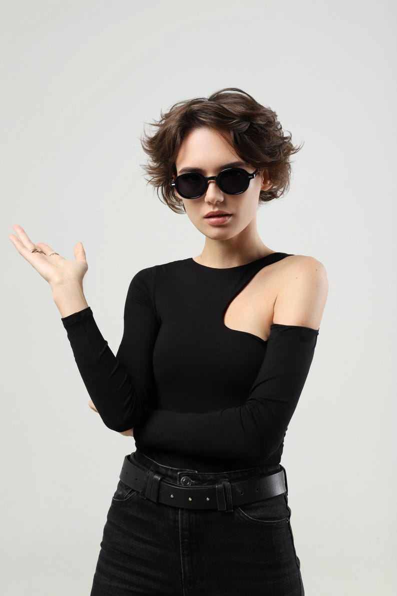 Woman wearing black round sunglasses in a wider fashion portrait, showing the overall scale and styling of the frame.