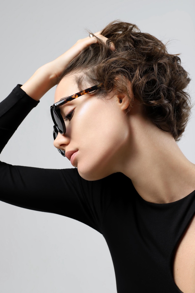 Woman wearing round black and tortoiseshell sunglasses, showing the frame shape and fit from the front.
