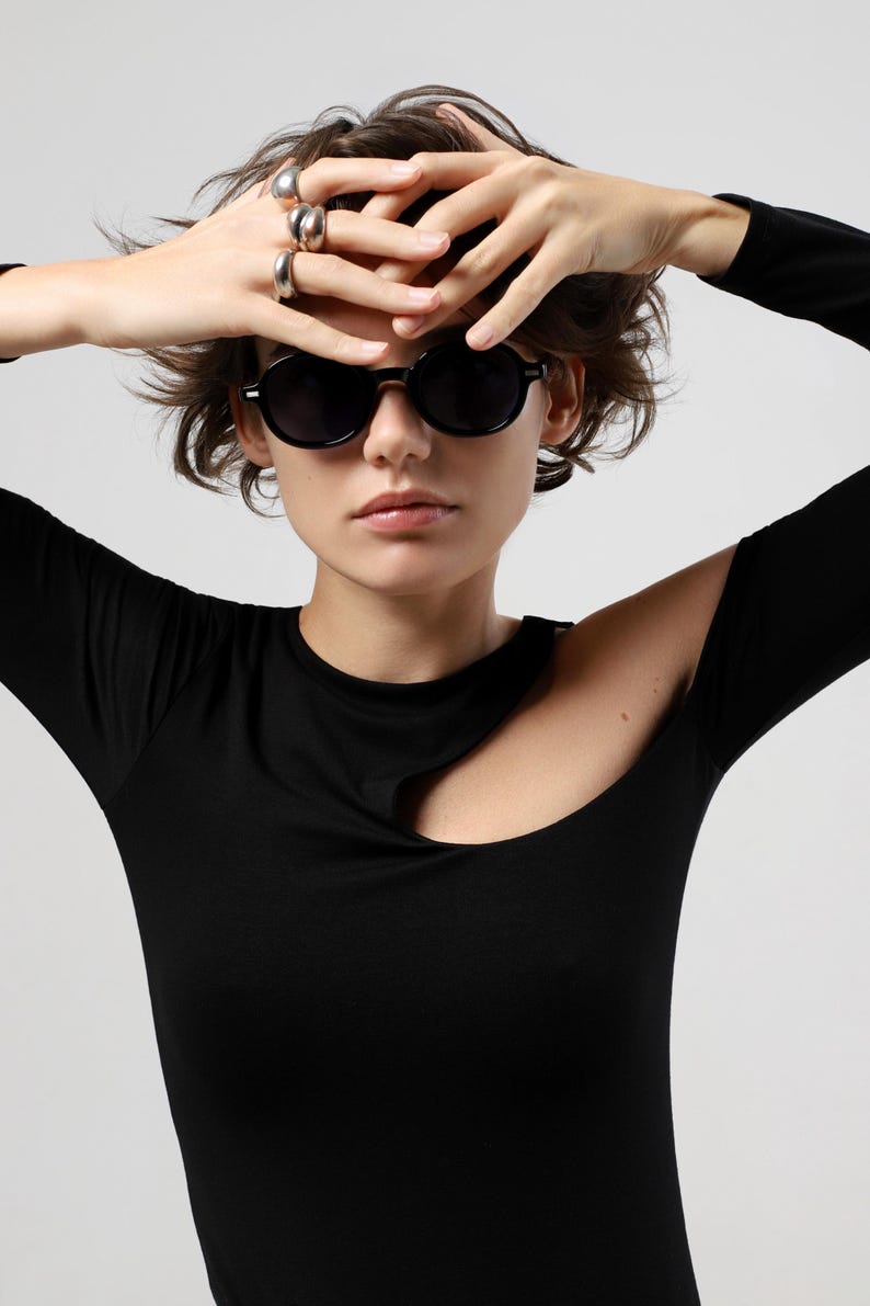 Front-facing woman wearing round black sunglasses with dark polarized lenses and a glossy frame.