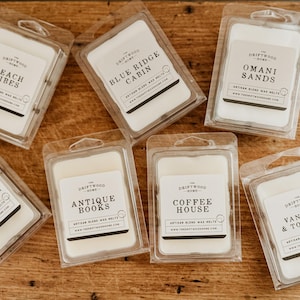 May include: Assortment of ten wax melts in clear plastic packaging. Each melt features a different scent and design with the brand name "The Driftwood Home" printed on the label.