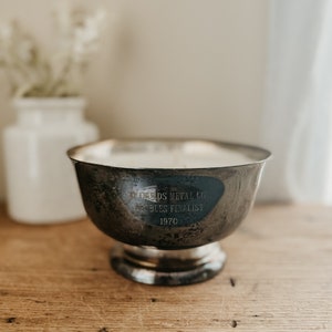 May include: A silver metal bowl with an inscription that reads "Reynolds Metal Co. Doubles Finalist 1970".