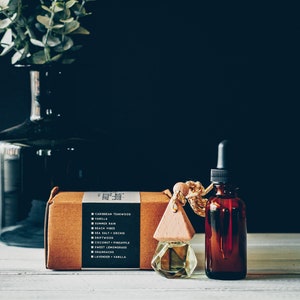 May include: A brown cardboard box with a list of scents, a wooden diffuser with a clear glass bottle, and a brown glass bottle with a dropper.