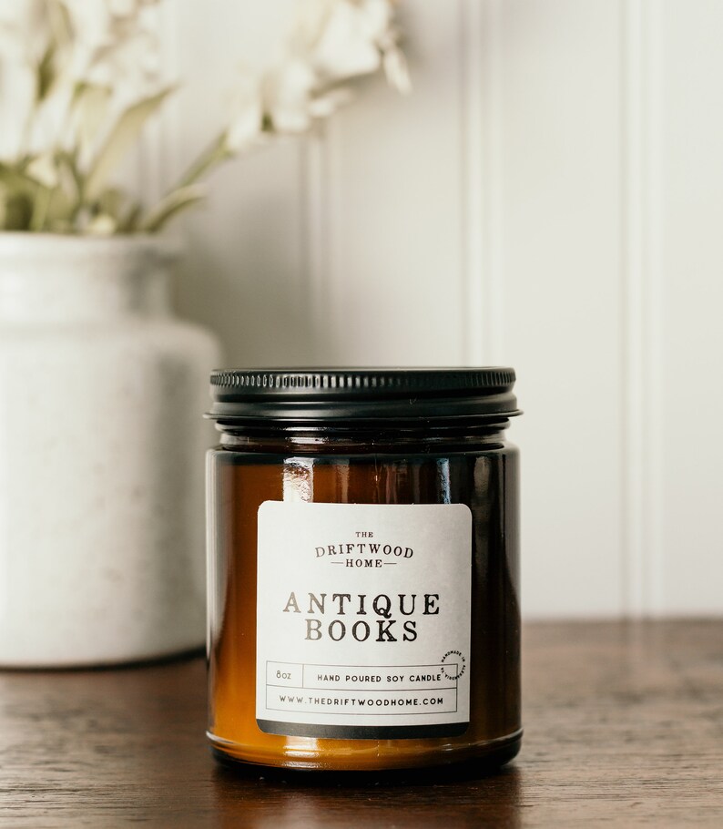 May include: A brown glass candle jar with a black lid. The label reads "The Driftwood Home" and "Antique Books". The candle is hand-poured soy and is 8 oz.