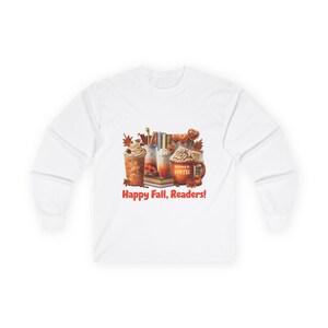 Op de afbeelding: Wit lange mouwen shirt met een herfstthema grafisch ontwerp. De afbeelding toont koffiedranken, boeken en de tekst "Happy Fall, Readers!" in het rood. Het ontwerp bevat herfstbladeren en een koffiemok.