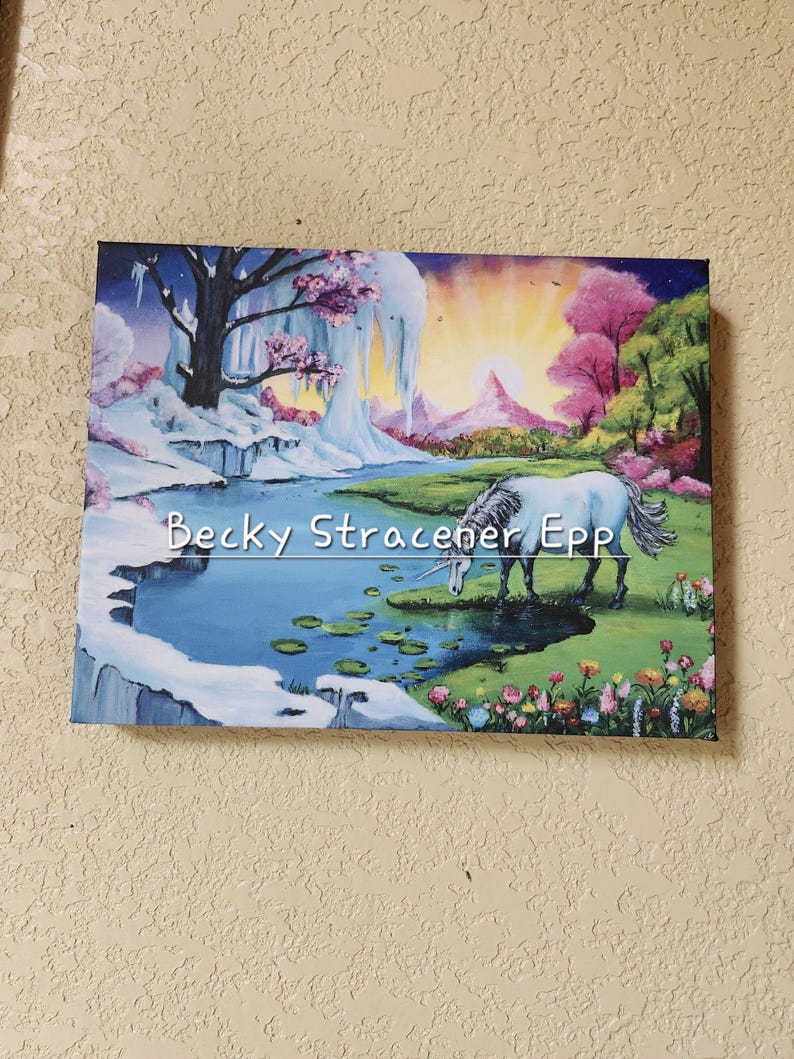 Puede incluir: Una pintura sobre lienzo que representa un paisaje sereno con un unicornio bebiendo de un estanque. La obra presenta una escena invernal con nieve, hielo y una colorida puesta de sol. El texto en la pintura dice "Becky Stracener Epp".