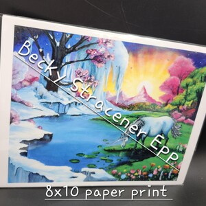 Puede incluir: Una impresi&oacute;n en papel de 8x10 que presenta un paisaje de fantas&iacute;a con un unicornio. La obra de arte representa una escena serena con una cascada, un lago y una colorida puesta de sol. La impresi&oacute;n tiene el texto "Becky Stracener EPP".