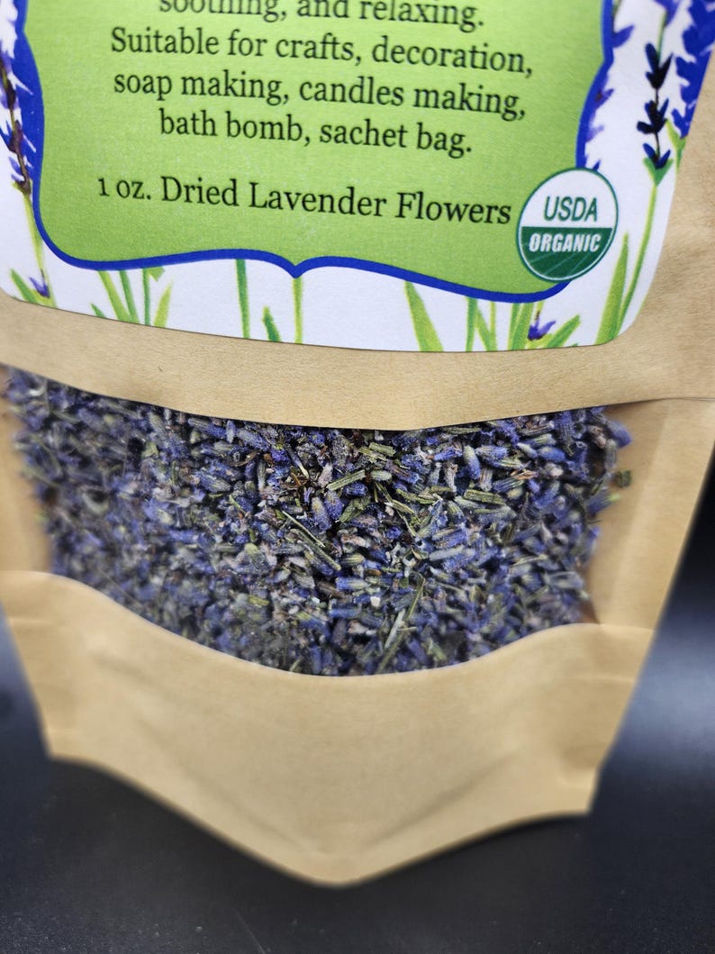 以下が含まれることがあります： 乾燥ラベンダーの花が入った茶色の紙袋のクローズアップ。袋には「1 oz. Dried Lavender Flowers USDA ORGANIC」と書かれた緑色のラベルが付いています。ラベンダーは紫と緑の混合です。