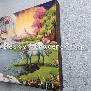 Puede incluir: Una impresi&oacute;n art&iacute;stica en lienzo que representa un unicornio bebiendo de un estanque en un paisaje de fantas&iacute;a. La obra de arte incluye una cascada, flores coloridas y el texto "Becky Stracener Epp". El fondo presenta una puesta de sol y &aacute;rboles rosas.