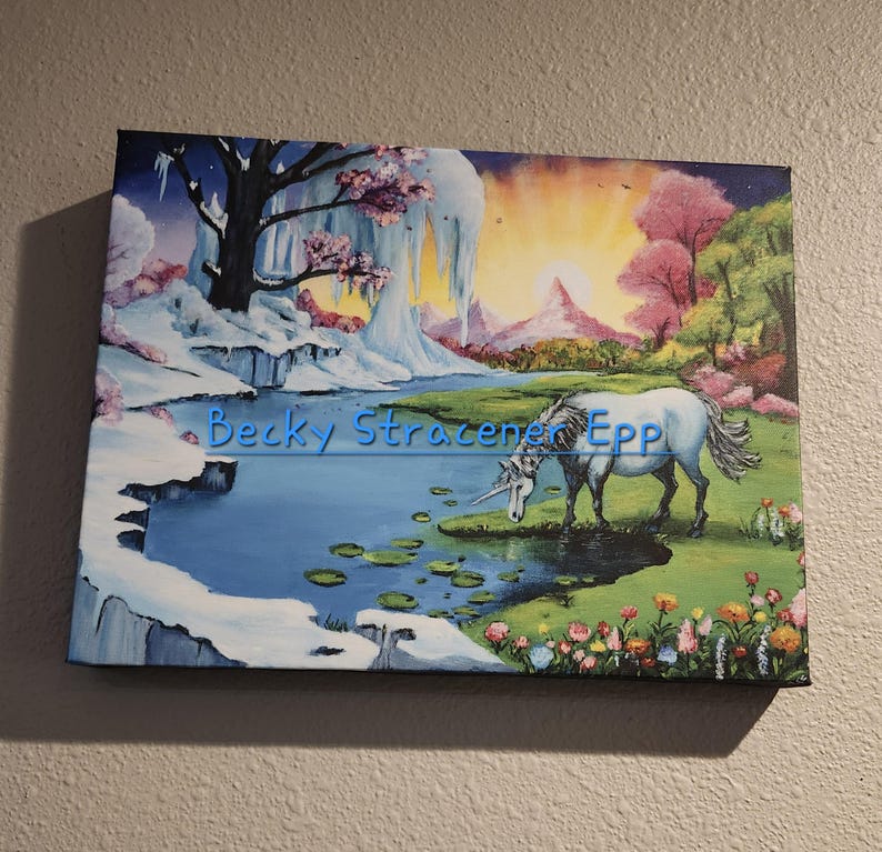 Puede incluir: Una pintura sobre lienzo representa un paisaje sereno con un unicornio blanco pastando cerca de un estanque. La obra de arte presenta una mezcla de paisajes invernales y primaverales, con nieve, hielo y flores floreciendo. El nombre del artista, "Becky Stracener Epp", es visible.