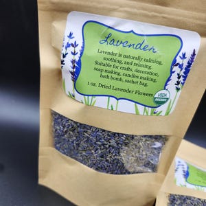 以下が含まれることがあります： 乾燥ラベンダーの花が入った茶色の紙袋。各バッグには「ラベンダー」という言葉と、クラフトや石鹸作りなど、製品の用途を説明するテキストが記載されたラベルが付いています。ラベルには、内容物がUSDAオーガニックであることも記載されています。