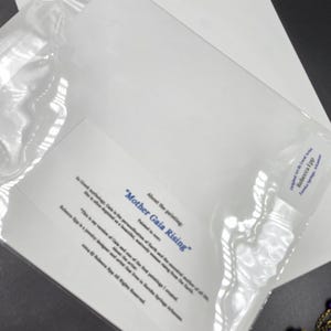 K&ouml;nnte beinhalten: Ein Druck von "Mother Gaia Rising" von Rebecca Epp, in einer transparenten Plastikh&uuml;lle. Der Druck enth&auml;lt Text, der die Inspiration des Gem&auml;ldes aus der griechischen Mythologie beschreibt. Das Kunstwerk ist auf wei&szlig;em Papier.