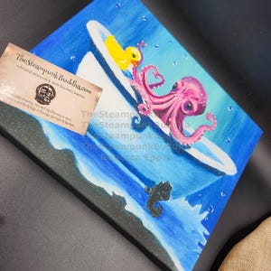 May include: A whimsical painting depicts a pink octopus in a bathtub with a yellow rubber ducky. The artwork is set against a blue background with water and bubbles, and a black sea creature. The Steampunk Buddha.com is visible.