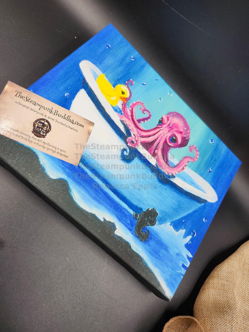 May include: A whimsical painting depicts a pink octopus in a bathtub with a yellow rubber ducky. The artwork is set against a blue background with water and bubbles, and a black sea creature. The Steampunk Buddha.com is visible.