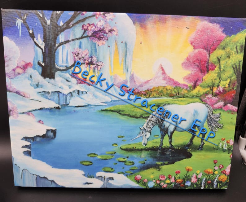 Puede incluir: Una pintura sobre lienzo representa un paisaje sereno con un unicornio blanco bebiendo de un estanque azul. La escena incluye acantilados cubiertos de nieve, &aacute;rboles rosados ​​en flor y una vibrante puesta de sol. El texto "Becky Stracener ERP" est&aacute; en la imagen.