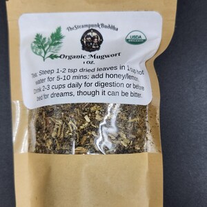 May include: A brown paper bag with a clear window displaying dried herbs. The label reads "Organic Mugwort" with instructions for tea preparation. The Steampunk Buddha logo and USDA Organic seal are also visible.