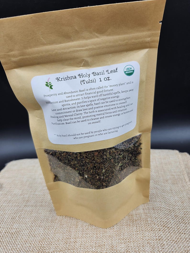 May include: A brown paper bag of Krishna Holy Basil Leaf (Tulsi) with a USDA Organic label. The bag contains dried basil leaves and has a white label with text describing the herb's uses and warnings. The bag is 1 oz.