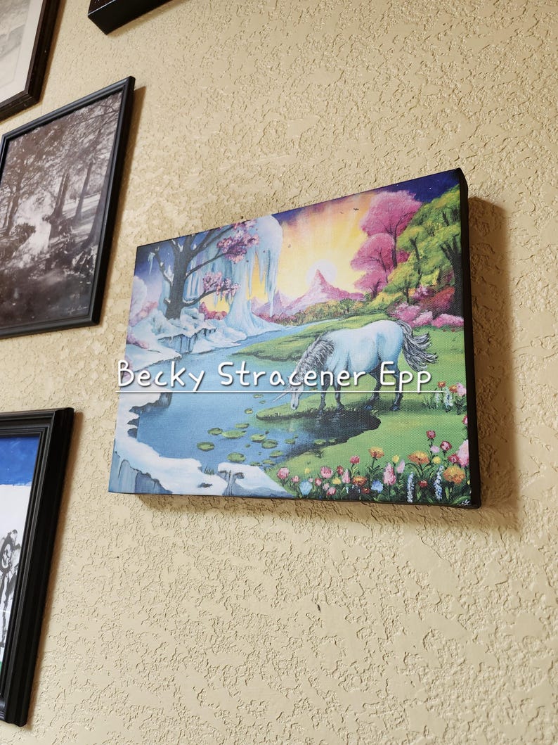Puede incluir: Una impresi&oacute;n en lienzo que representa un paisaje de fantas&iacute;a con un unicornio blanco bebiendo de un arroyo. La obra presenta una escena colorida con &aacute;rboles rosas y verdes, una cascada y una puesta de sol. El texto "Becky Stracener EPP" es visible.