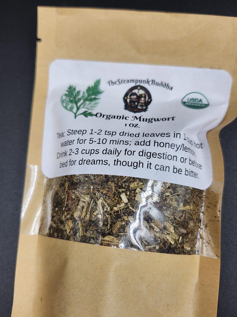 May include: A brown paper bag containing organic mugwort tea. The bag has a white label with the text "The Steampunk Buddha" and "Organic Mugwort." The label also includes instructions for brewing the tea and a USDA organic seal.