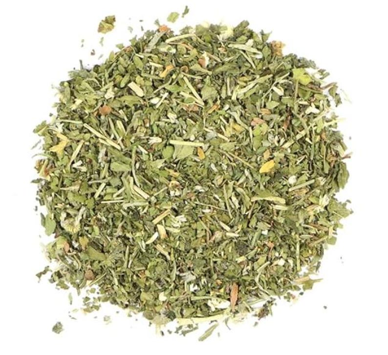 Puede incluir: Primer plano de una mezcla de hierbas y especias secas, con tonos verdes, amarillos y marrones. La mezcla est&aacute; finamente picada, mostrando hojas y tallos. La imagen est&aacute; sobre un fondo blanco liso, resaltando los colores naturales del producto.