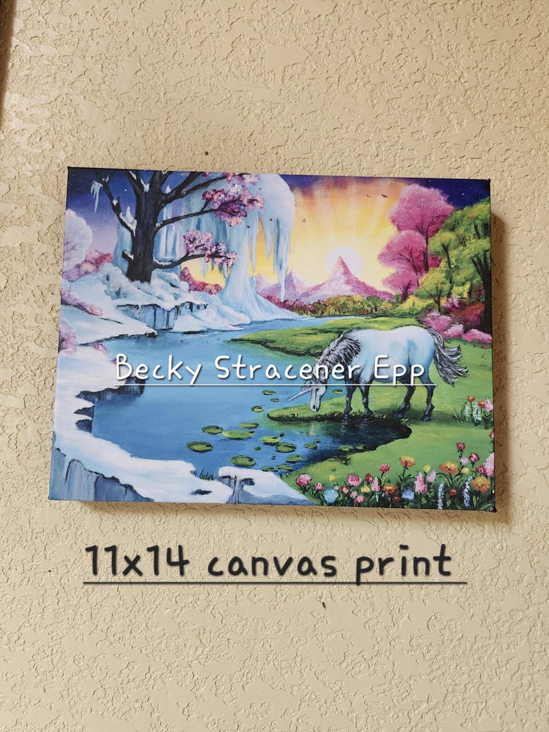 Puede incluir: Impresi&oacute;n en lienzo de 28x36 cm que representa un paisaje de fantas&iacute;a con un unicornio blanco bebiendo de un estanque. La obra de arte incluye una zona nevada, &aacute;rboles rosas y una puesta de sol. El nombre del artista, Becky Stracener Epp, es visible.