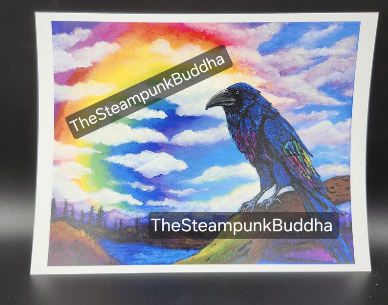 Op de afbeelding: Een levendige print met een gedetailleerde illustratie van een raaf die op een rots zit, tegen een achtergrond van een regenboog en een bewolkte lucht. De raaf is afgebeeld met blauwe en paarse veren. De tekst "TheSteampunkBuddha" staat over de afbeelding.