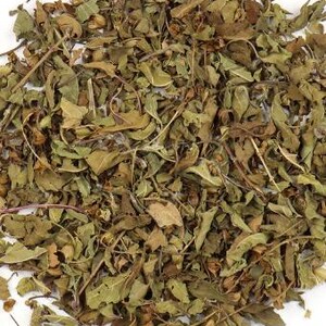 May include: Close-up of dried, loose leaf herbs with a mix of green, brown, and tan colors. The leaves and stems are scattered across a white surface, showing various textures and shapes. The image highlights the natural, organic appearance of the herbs.