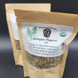 May include: Two brown paper pouches of Organic Mugwort tea. Each pouch has a white label with green botanical illustrations and text that reads "The Steampunk Buddha" and "USDA Organic". The label also includes instructions for brewing the tea.