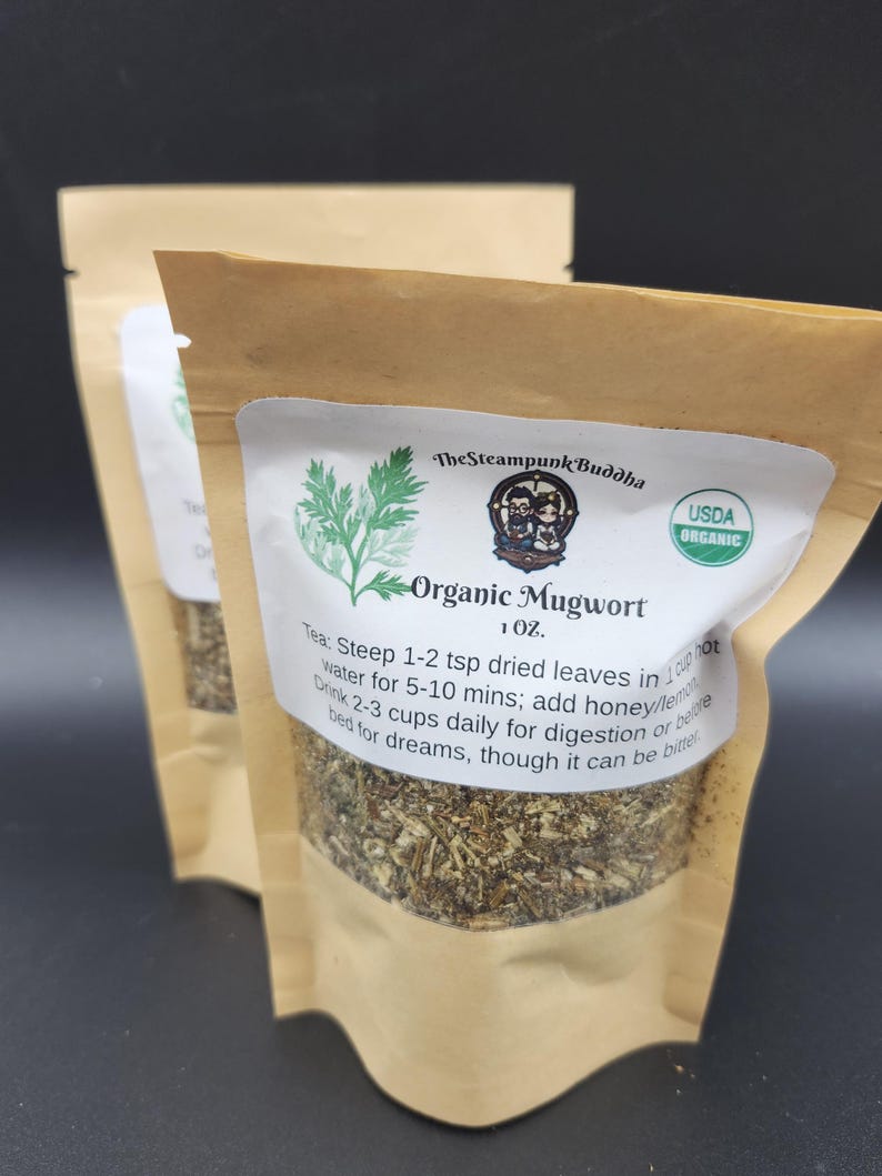May include: Two brown paper pouches of Organic Mugwort tea. Each pouch has a white label with green botanical illustrations and text that reads "The Steampunk Buddha" and "USDA Organic". The label also includes instructions for brewing the tea.
